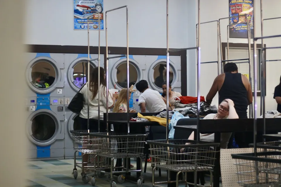 Customers use washers and folding tables inside Fresh Spin Laundry during the Community Care Day grand opening event.