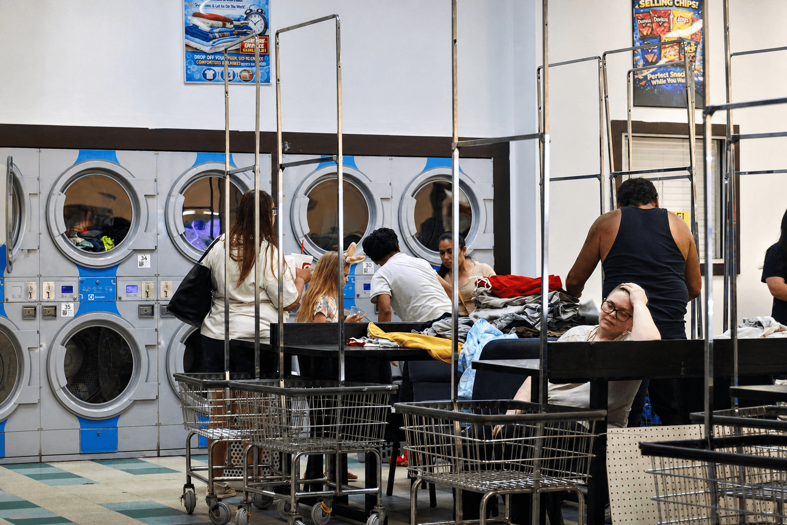 Customers using washers dryers carts and folding tables inside Fresh Spin Laundry